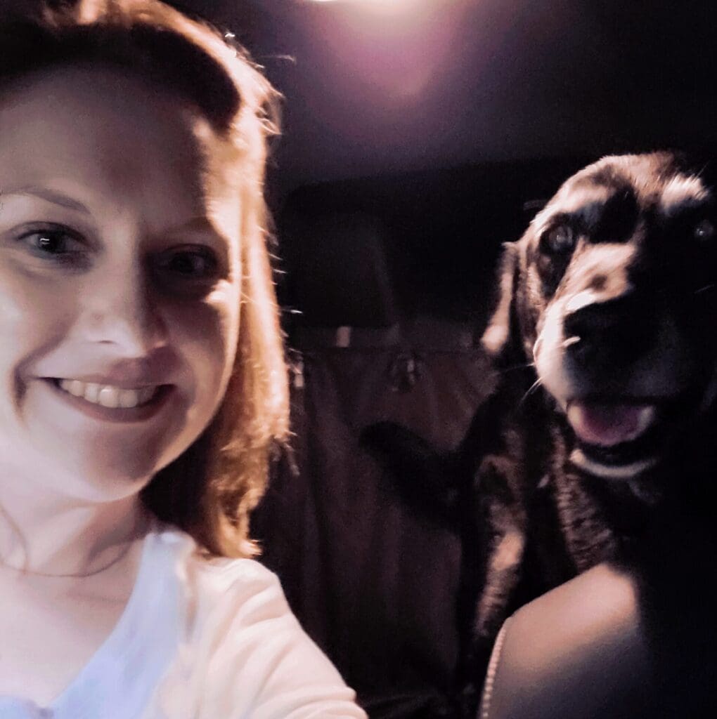 A woman and her dog taking a selfie inside of a car.
