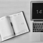 flat lay photography of unfold book beside macbook