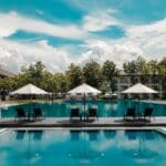 black outdoor lounge chair in between blue swimming pool under white cloudy blue sky