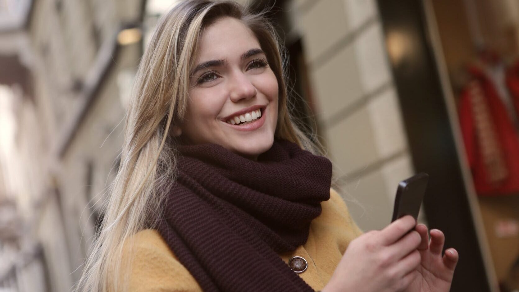 woman in brown scarf holding a smartphone