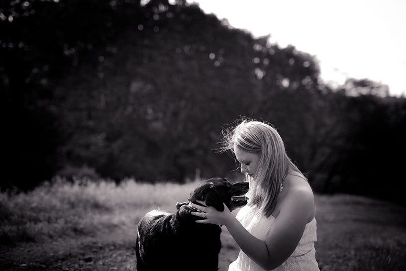 Black and White photo of a woman looking in her Dogs eyes. Her Black Lab is looking back at her.