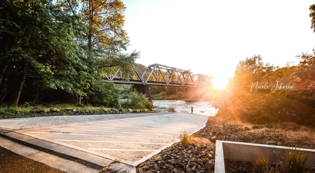 Sun sets behind a train trussell over the North Umpqua River at Amacher Park in Roseburg, Oregon